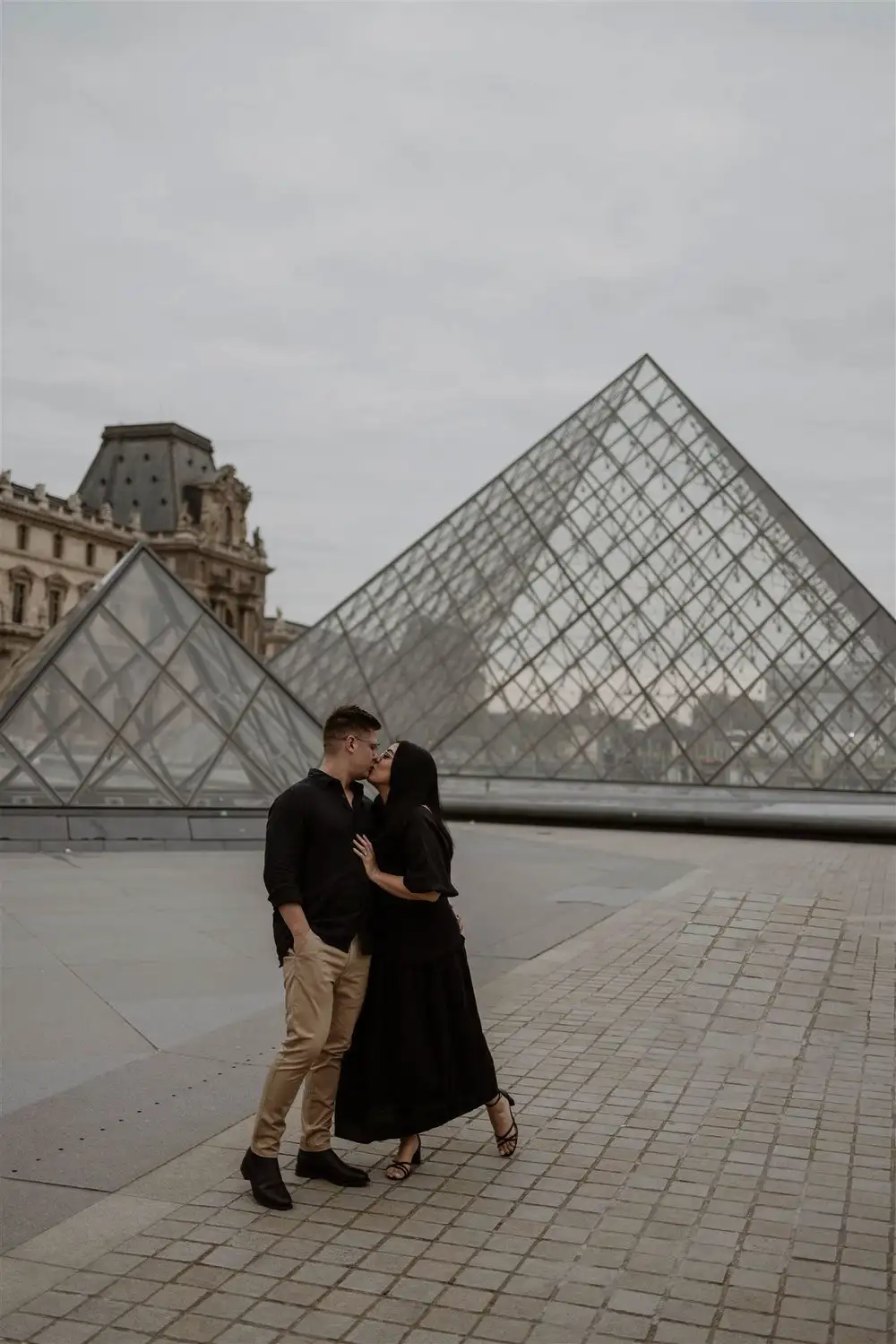 Couple embracing beside a glass pyramid