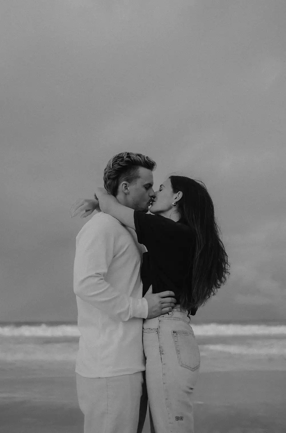 Black and white portrait of a couple kissing on the beach