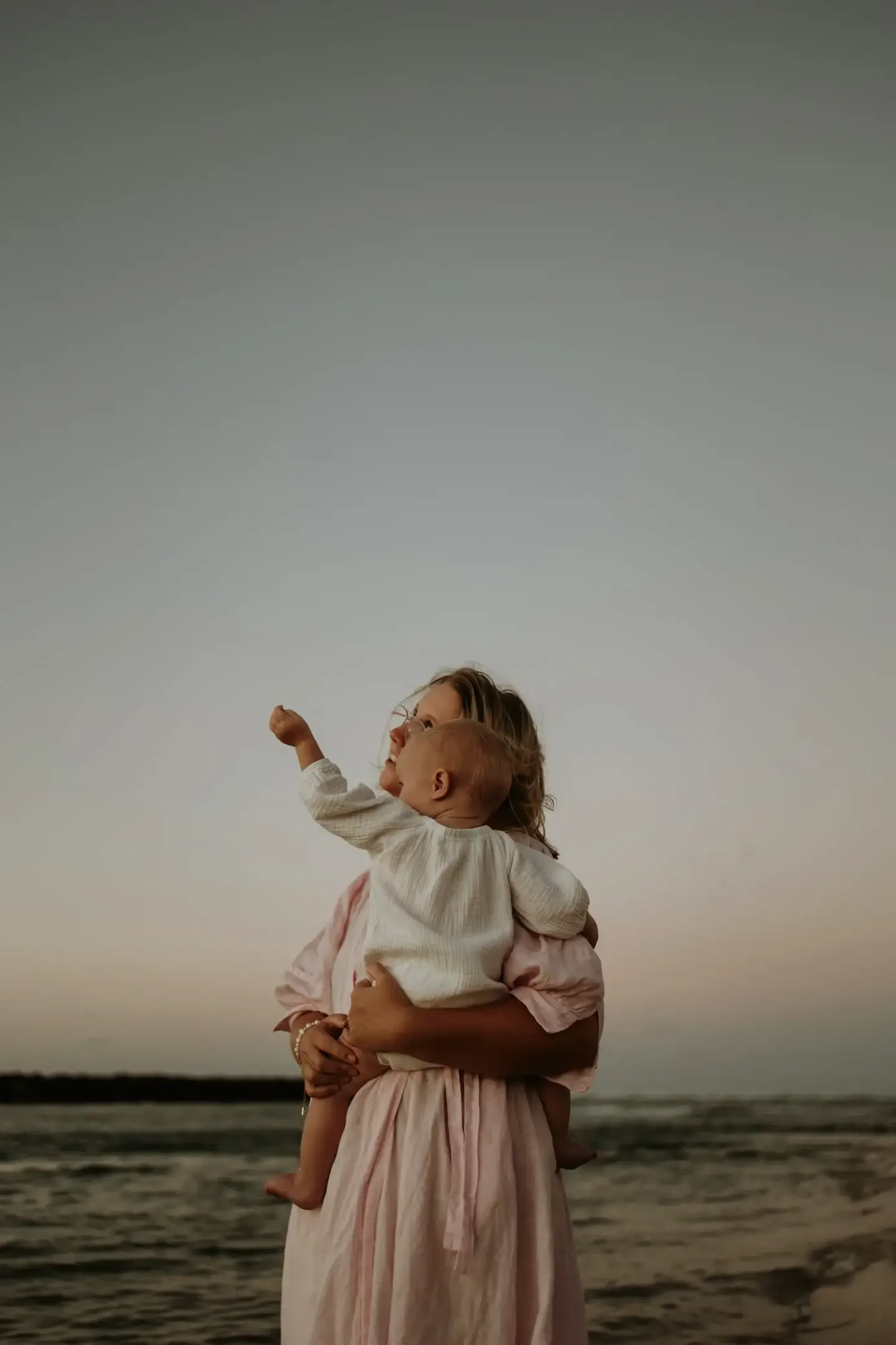 Woman holding a child at the beach in the evening light