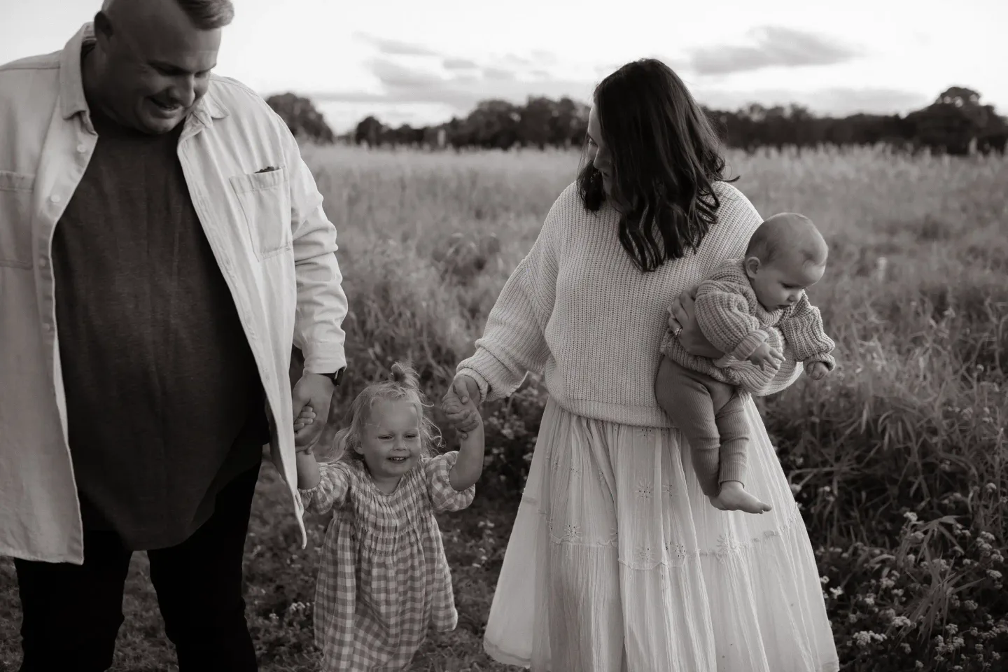 Parents walking through a grassy field with their children