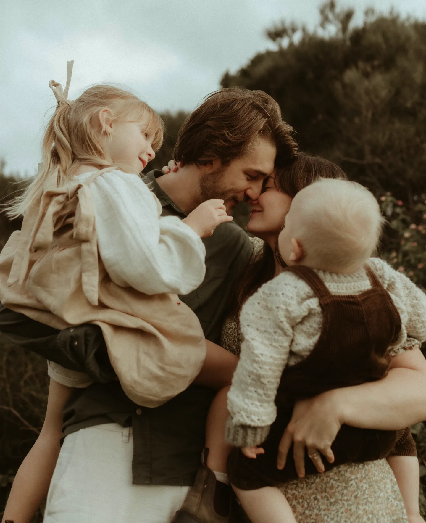 Parents cuddling their two young children outdoors